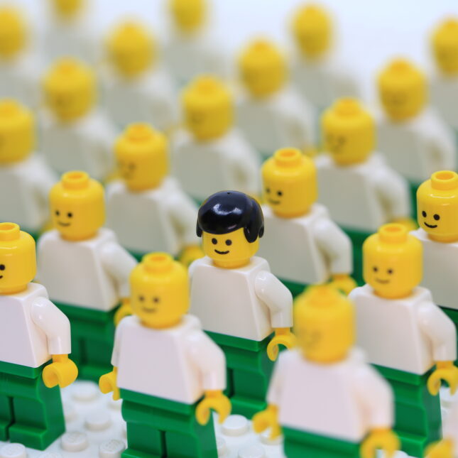 A stock photo of rows and rows of lego figurines, only one has hair