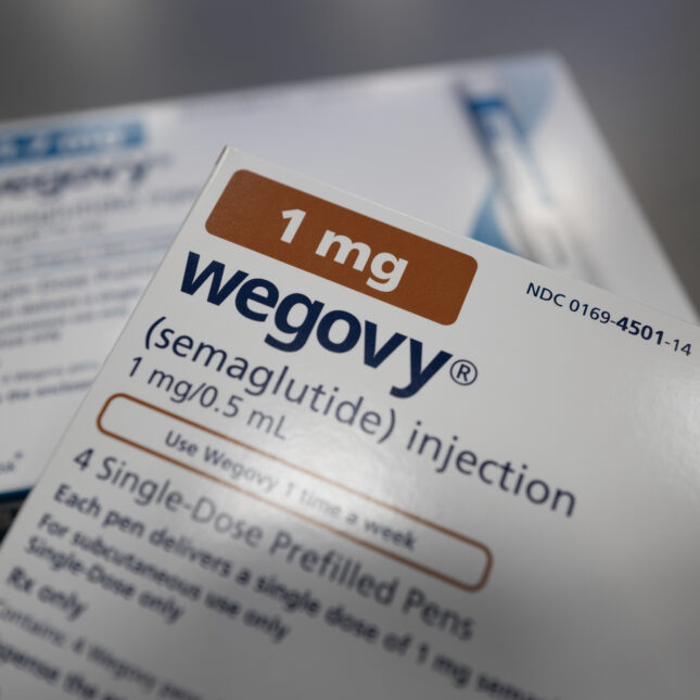 A box of Wegovy with brown labels in focus, its corner resting on a box of Wegovy with blue labels -- politics coverage from STAT