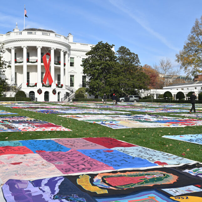 A red ribbon can be seen on the South Portico of the White House overlooking an AIDS Memorial Quilt display in the South Lawn of the White House before US President Joe Biden and First Lady Jill Biden delivers remarks to commemorate World AIDS Day on the South Lawn of the White House in Washington, DC, on December 1, 2024.